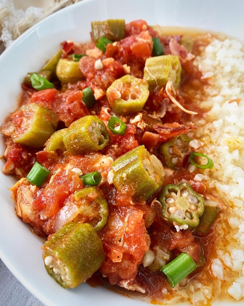 close up side view of Chicken with Okra & Tomatoes in a white bowl with cauliflower rice
