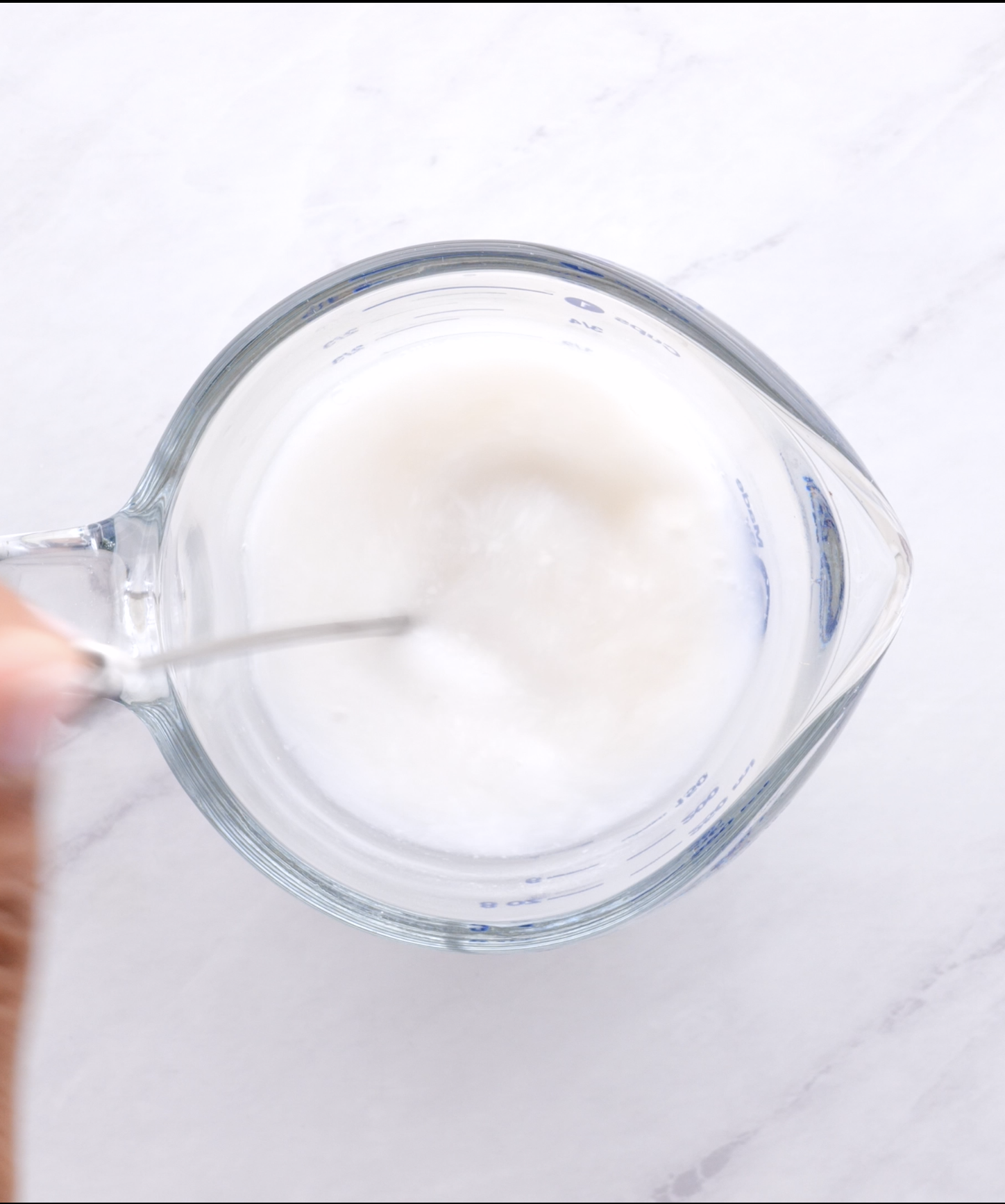 vinegar being whisked into vegan milk in a glass measuring cup to make vegan buttermilk