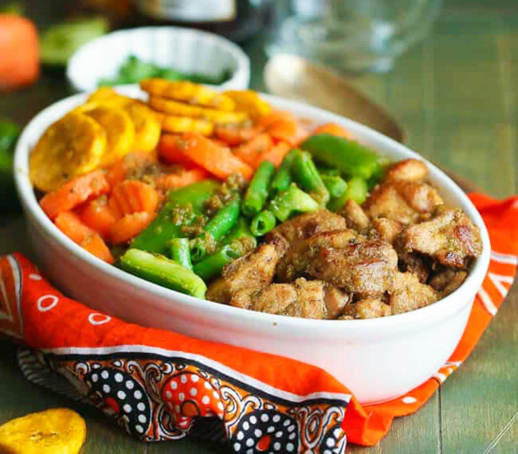 White bowl filled with chicken, fried plantains, carrots, and green beans.