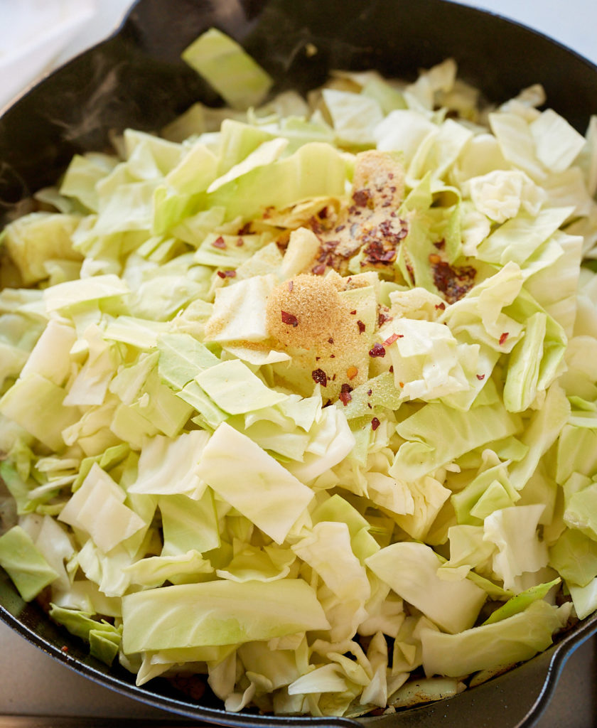 chopped cabbage in skillet with seasoning