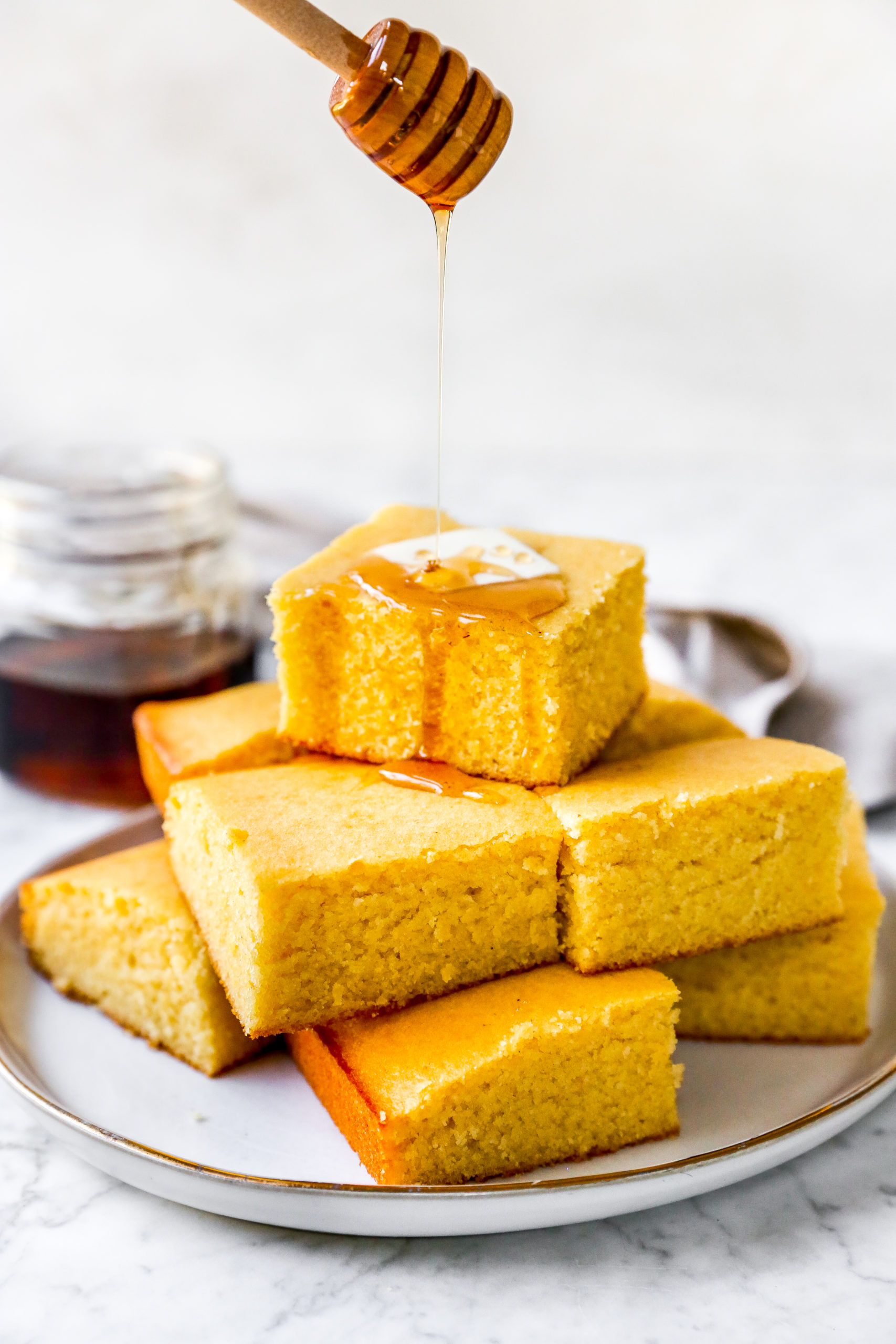 cornbread muffins in a stack with maple syrup drizzled on top and a pat of butter