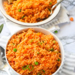 Two bowls of Jollof Rice with chicken in the background