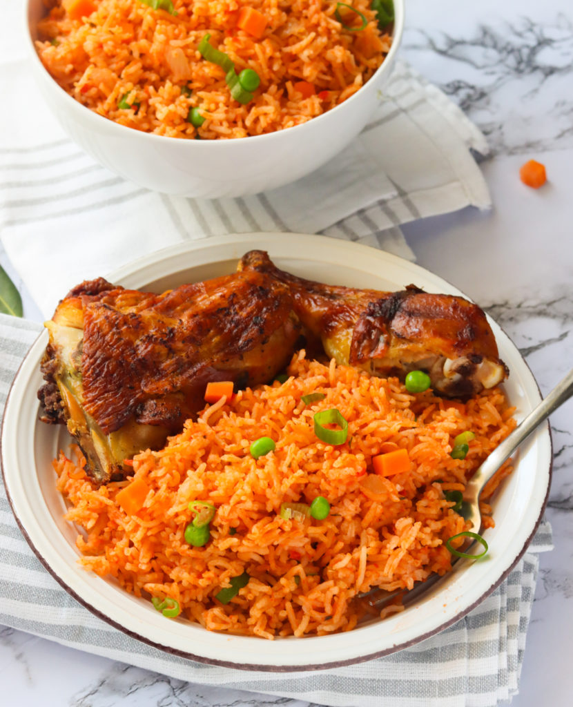 Jollof rice in a white bowl with baked chicken