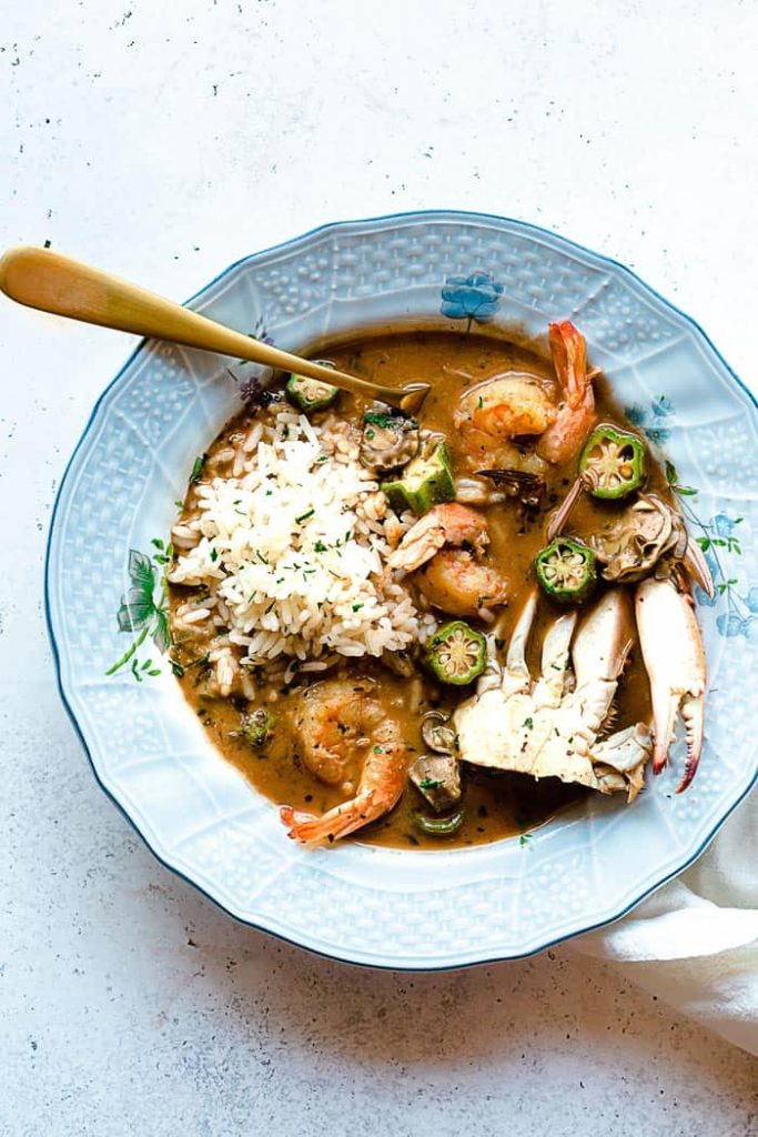 A blue bowl filled with seafood gumbo and okra ready to enjoy.