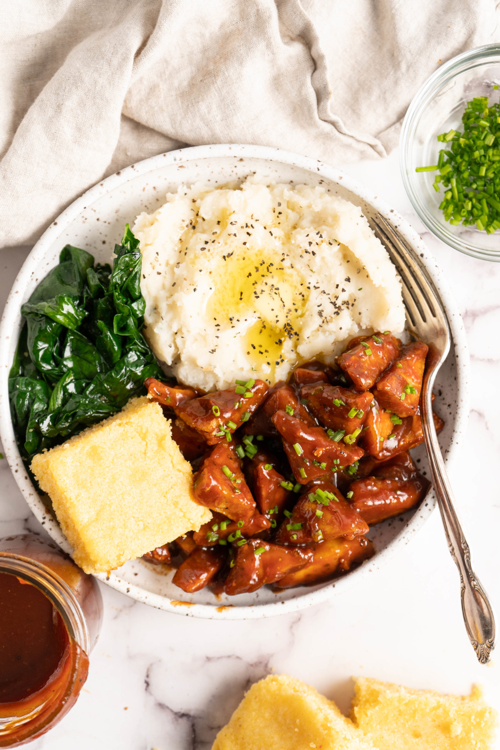 Vegan soul food bowl with mashed potatoes, BBQ tofu, cornbread, and collards.