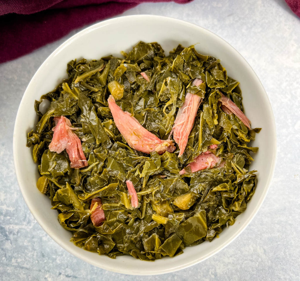 southern collard greens with ham hocks in a white bowl
