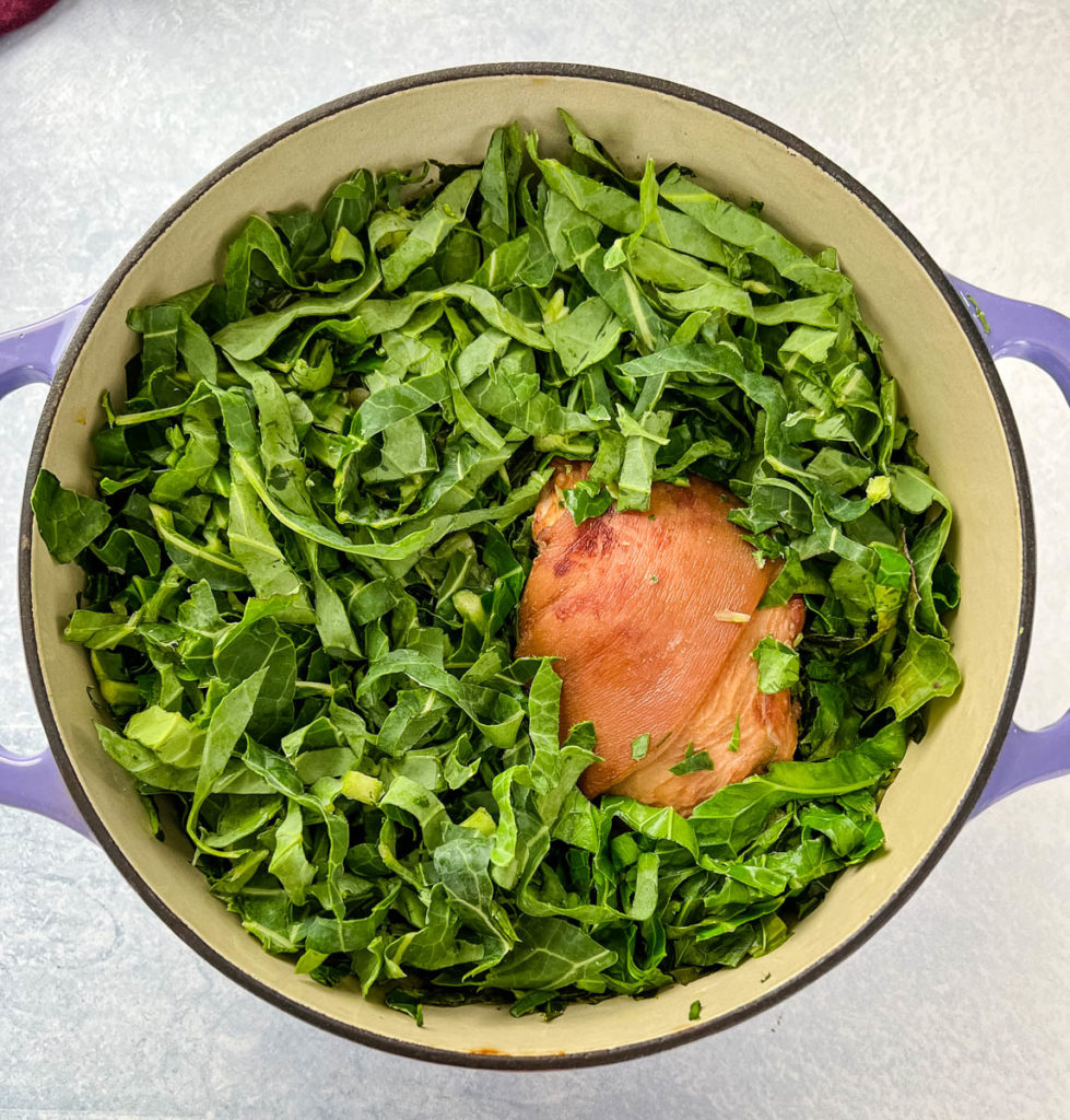 uncooked southern collard greens with ham hocks in a Dutch oven