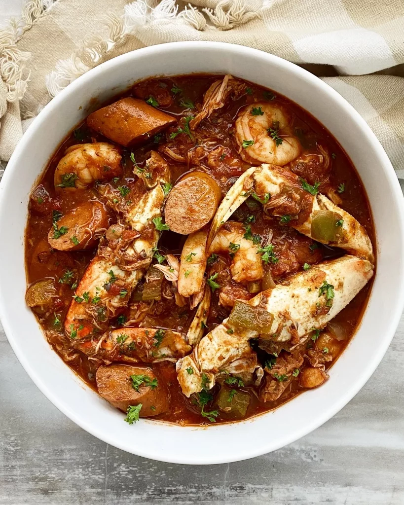 A white bowl of delicious slow cooker gumbo with sausage and seafood poking through.
