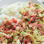jamaican corned beef and cabbage on white plate with white rice