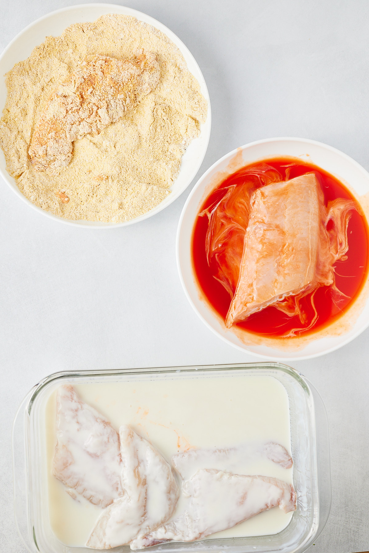 catfish dredging station with catfish filets in milk, hot sauce, and cornmeal mixture
