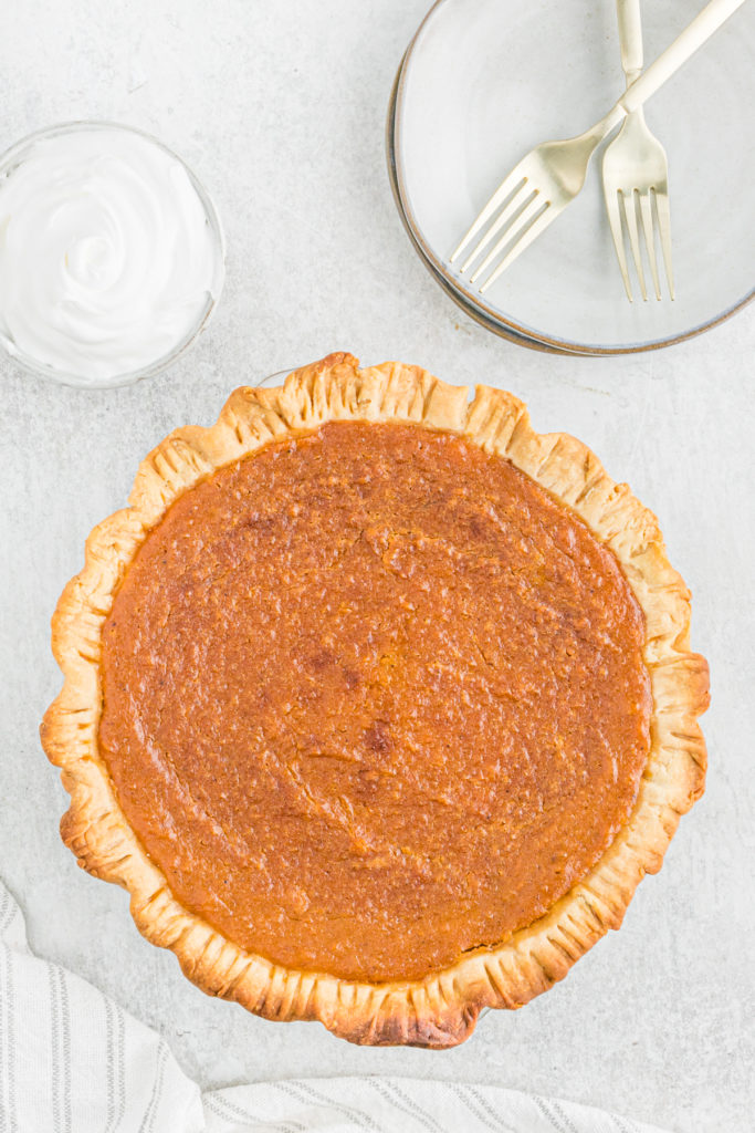 A beautiful top down shot of sweet potato pie against a gray background with a white and gray napkin.