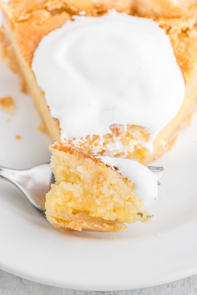 A slice of Southern pie on a white plate with a fork cutting through it to serve with whipped cream