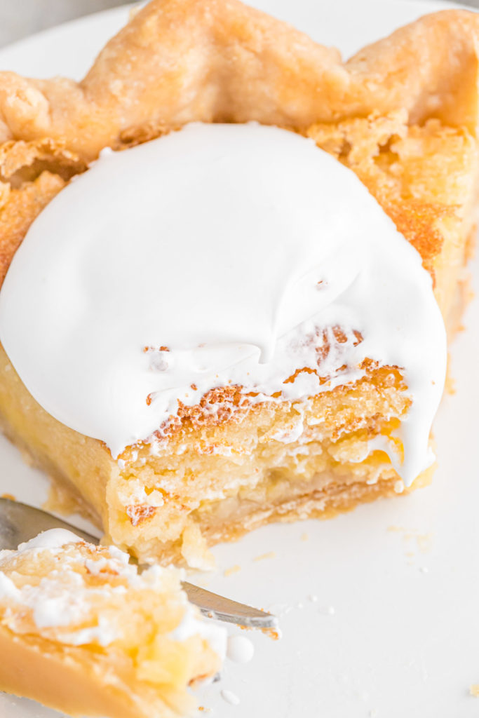 A slice of buttermilk pie being eaten with whipped cream on top