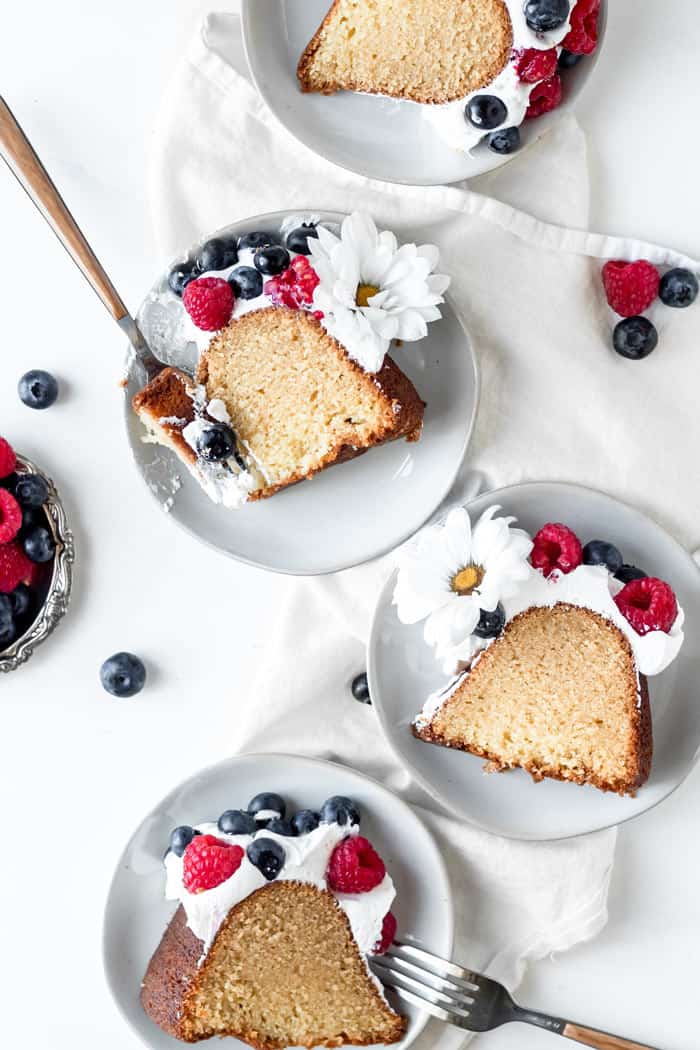 Butter Pound Cake served on white plates with berries and daisies