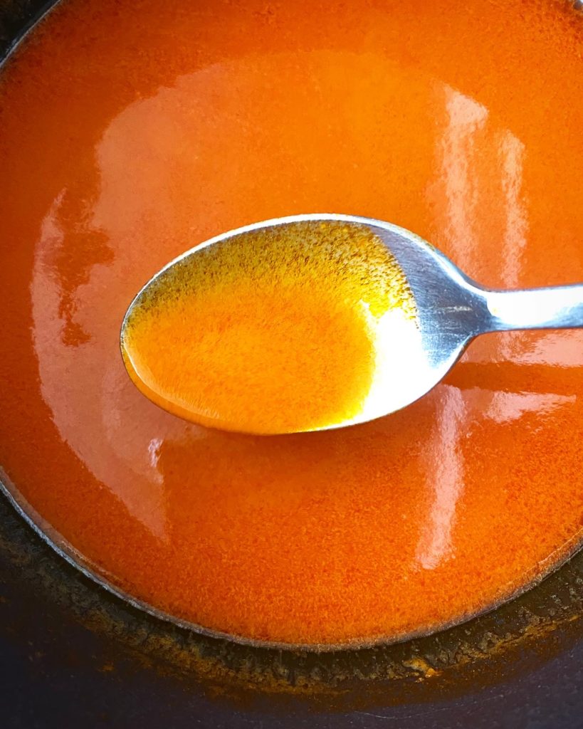 Close up up of cooked Homemade Buffalo Sauce in a black saucepan