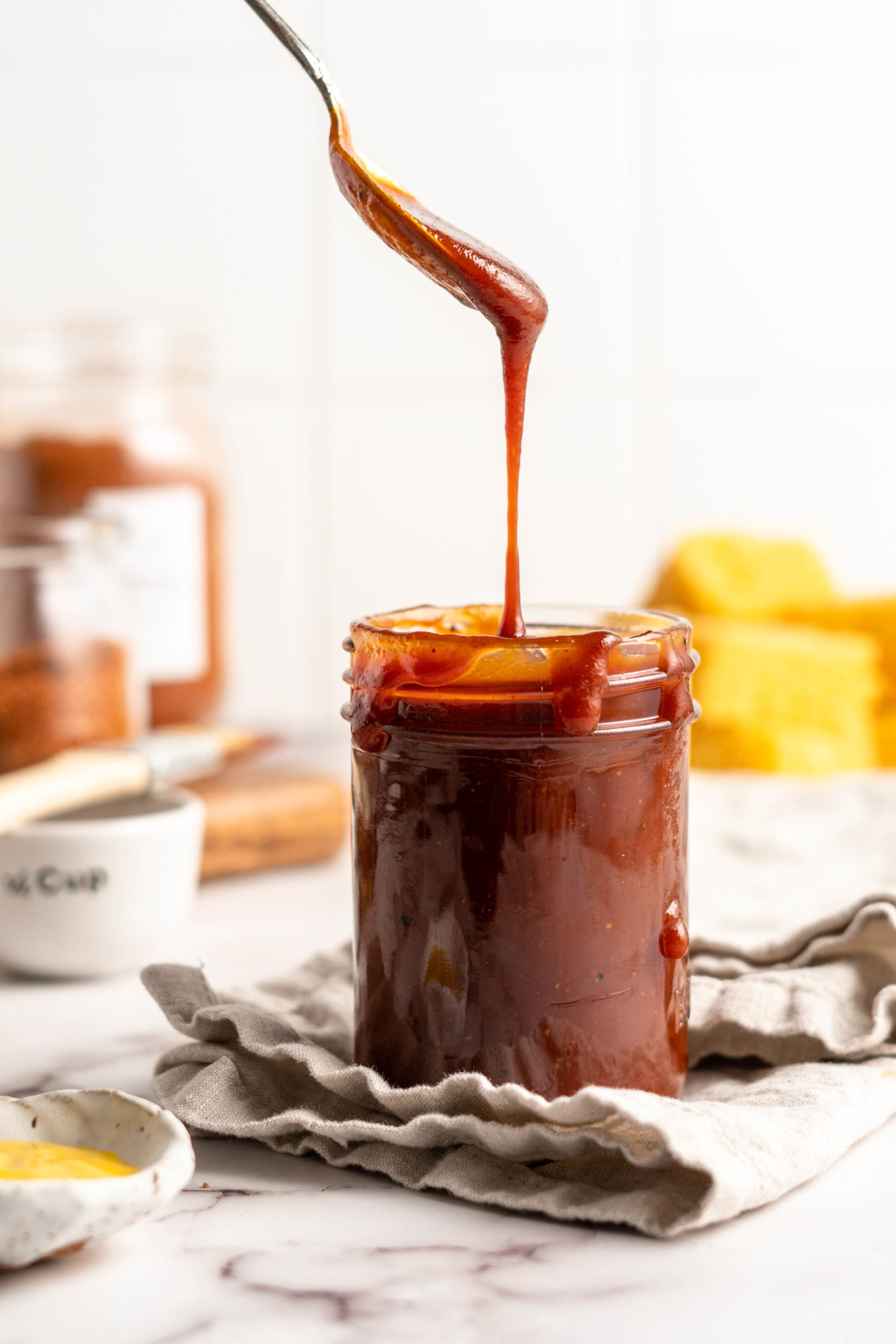 Barbecue sauce dripping from spoon into jar