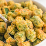 A close up of fried okra with a spoon taking some out