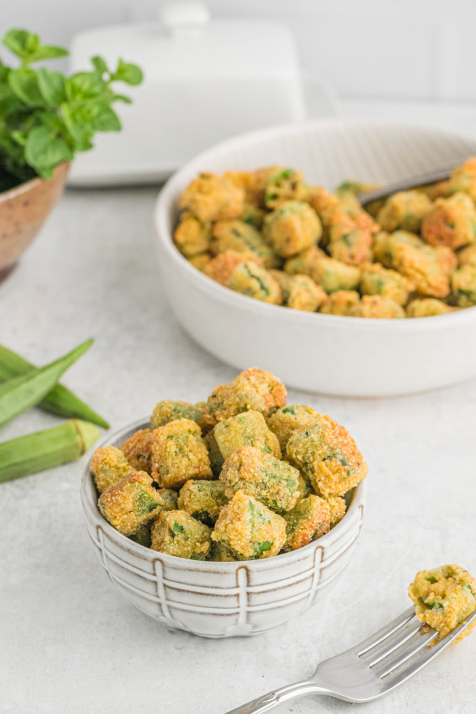 A bowl of okra that's fried with some in the background.