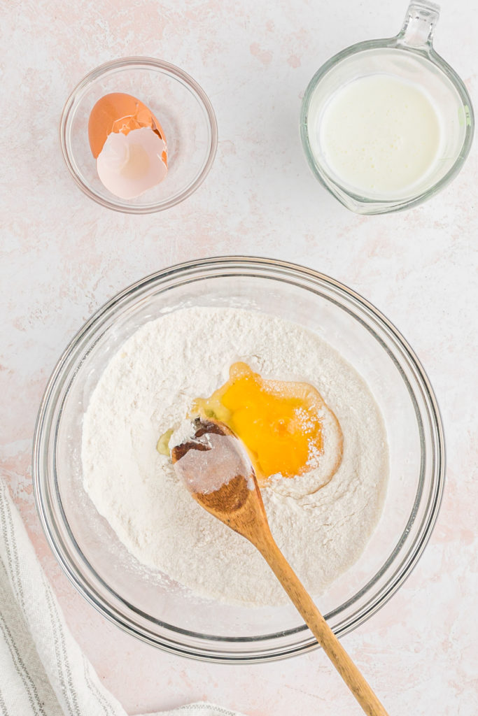 Eggs and buttermilk being stirred into a bowl of dry ingredients