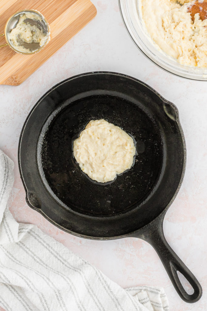 A pancake being fried in a cast iron skillet