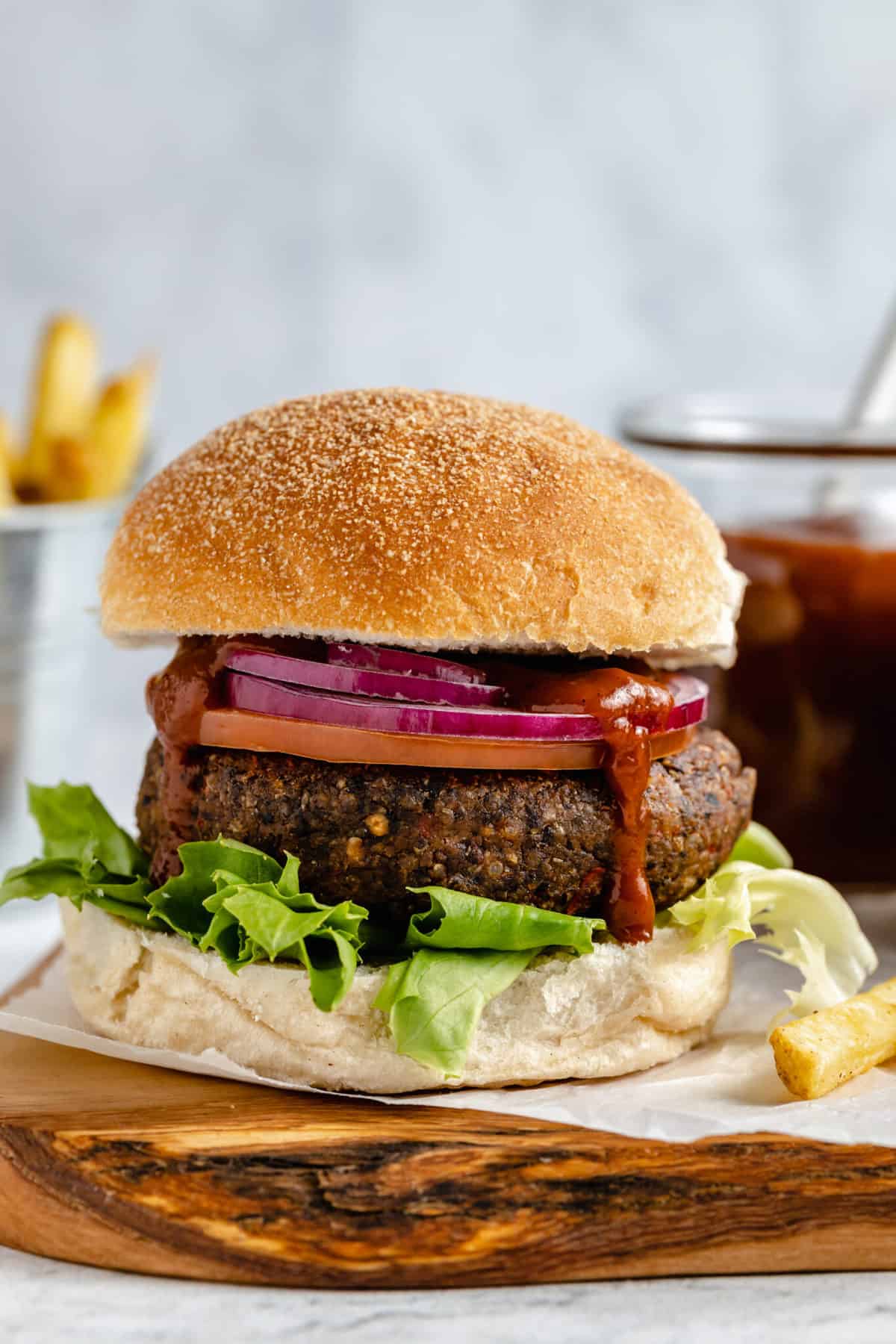 Vegan black bean and quinoa burger on wooden board with fries