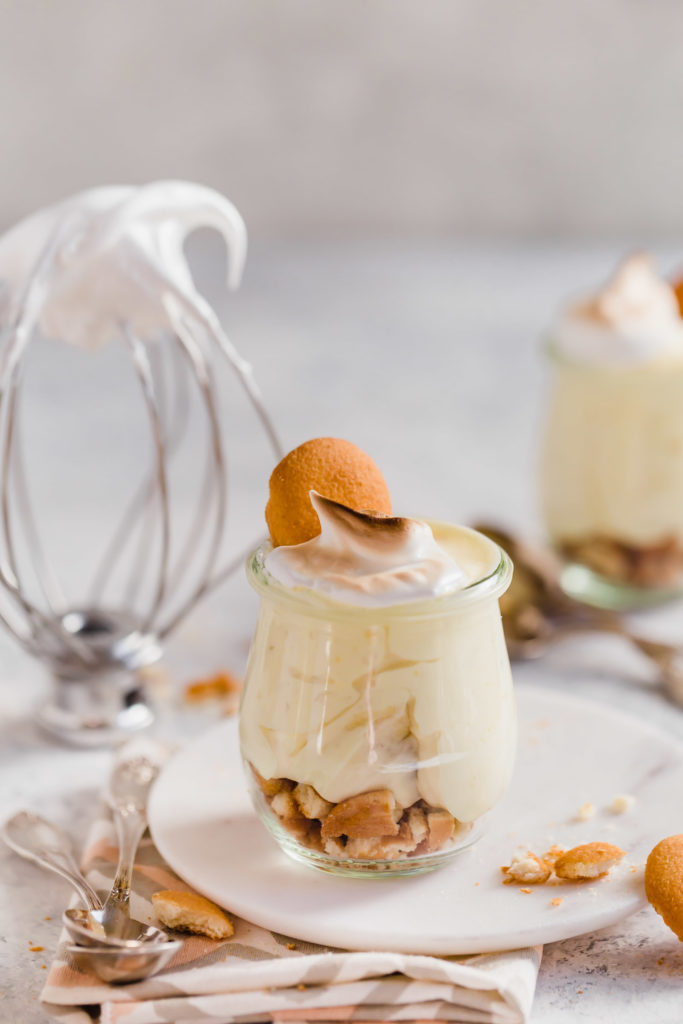 A Black Southern Banana Pudding in small glass containers with nilla wafers on top.