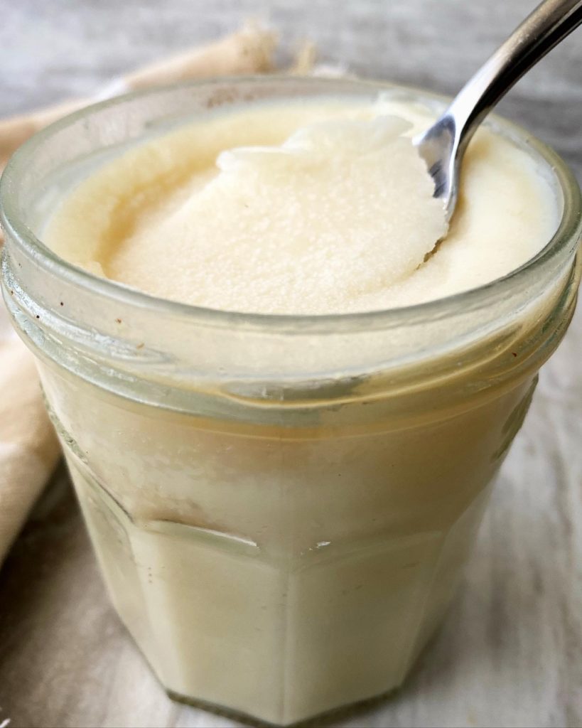 side view of mason jar of bacon grease with a spoon in it