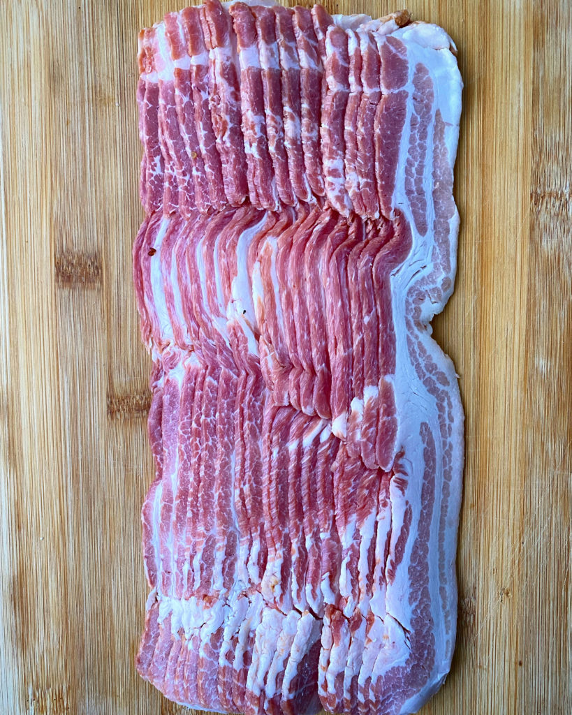 uncooked bacon on a wooden cutting board