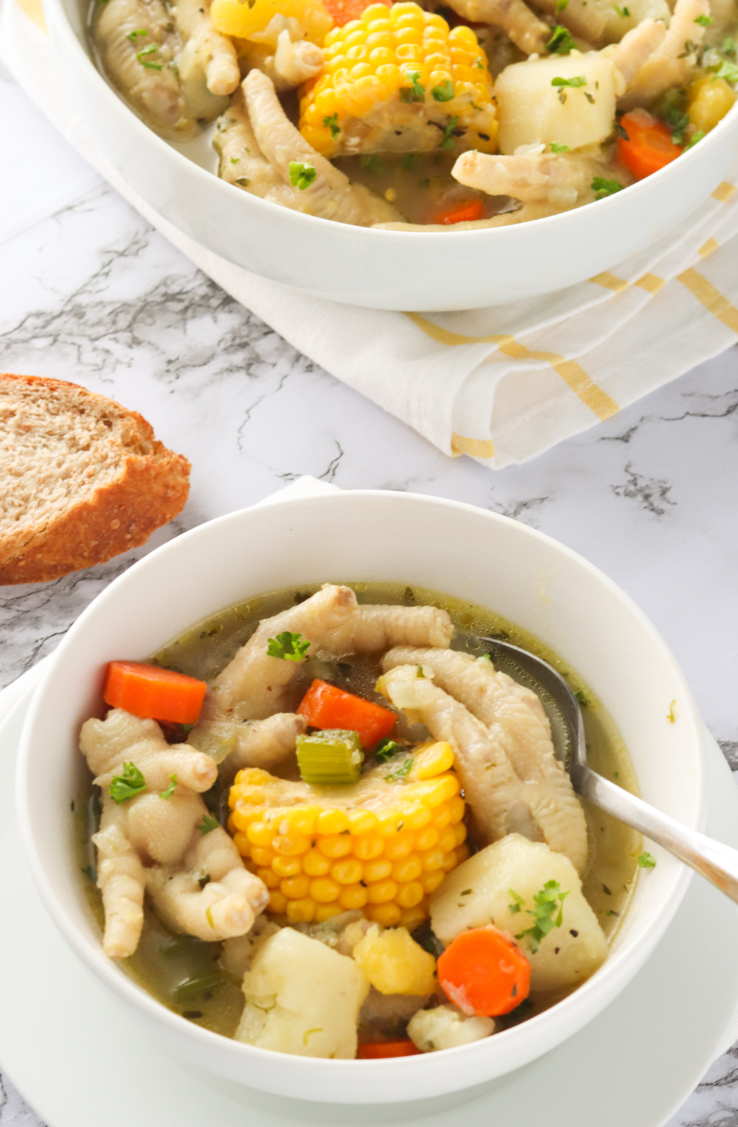 Two bowls of chicken feet soup with homemade bread