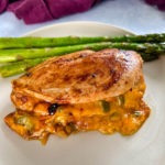 cajun stuffed chicken breast with cheese and andouille sausage on a plate with asparagus