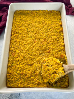 a spoonful of cornbread dressing in a white baking dish