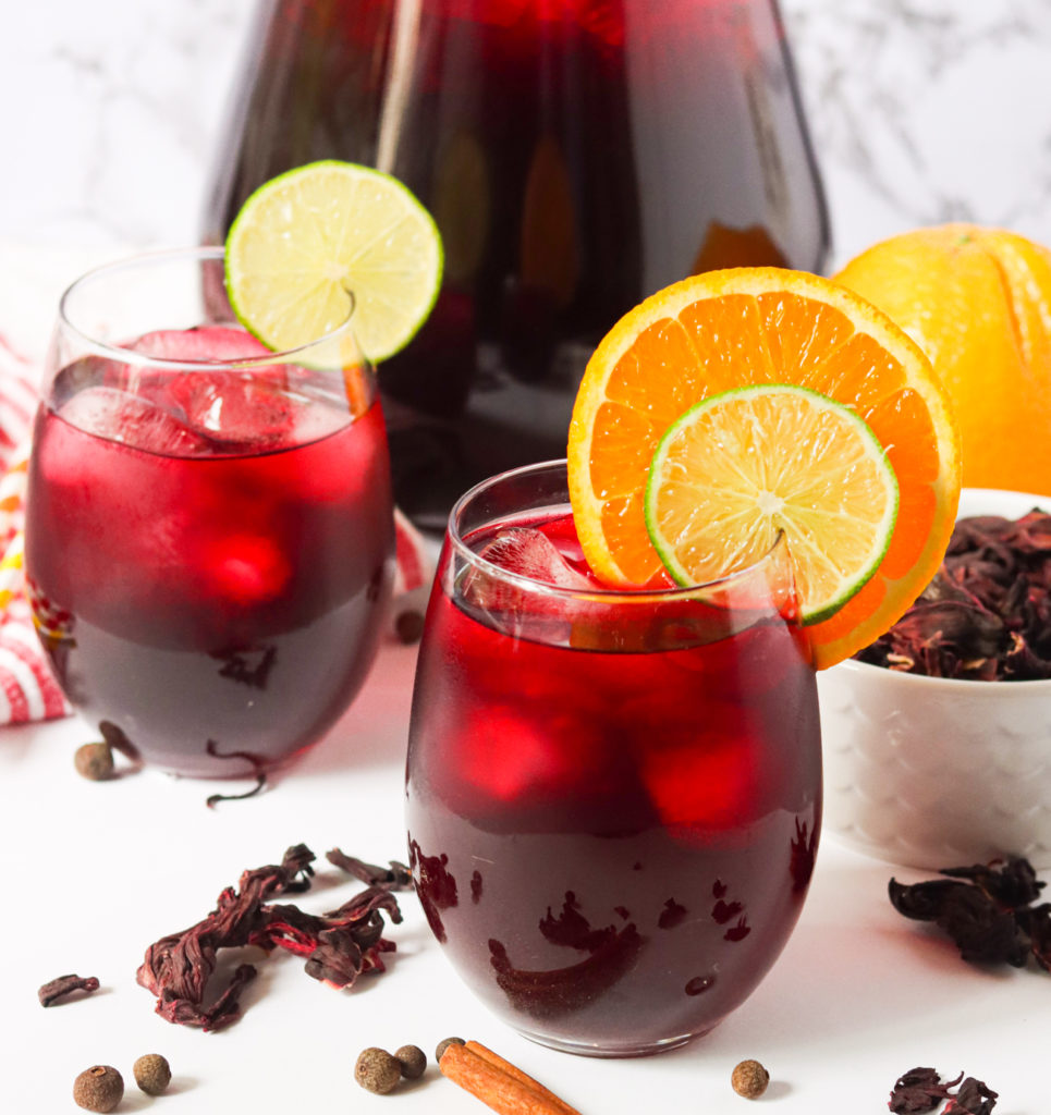 Two glasses of sorrel drink with lime and orange slices
