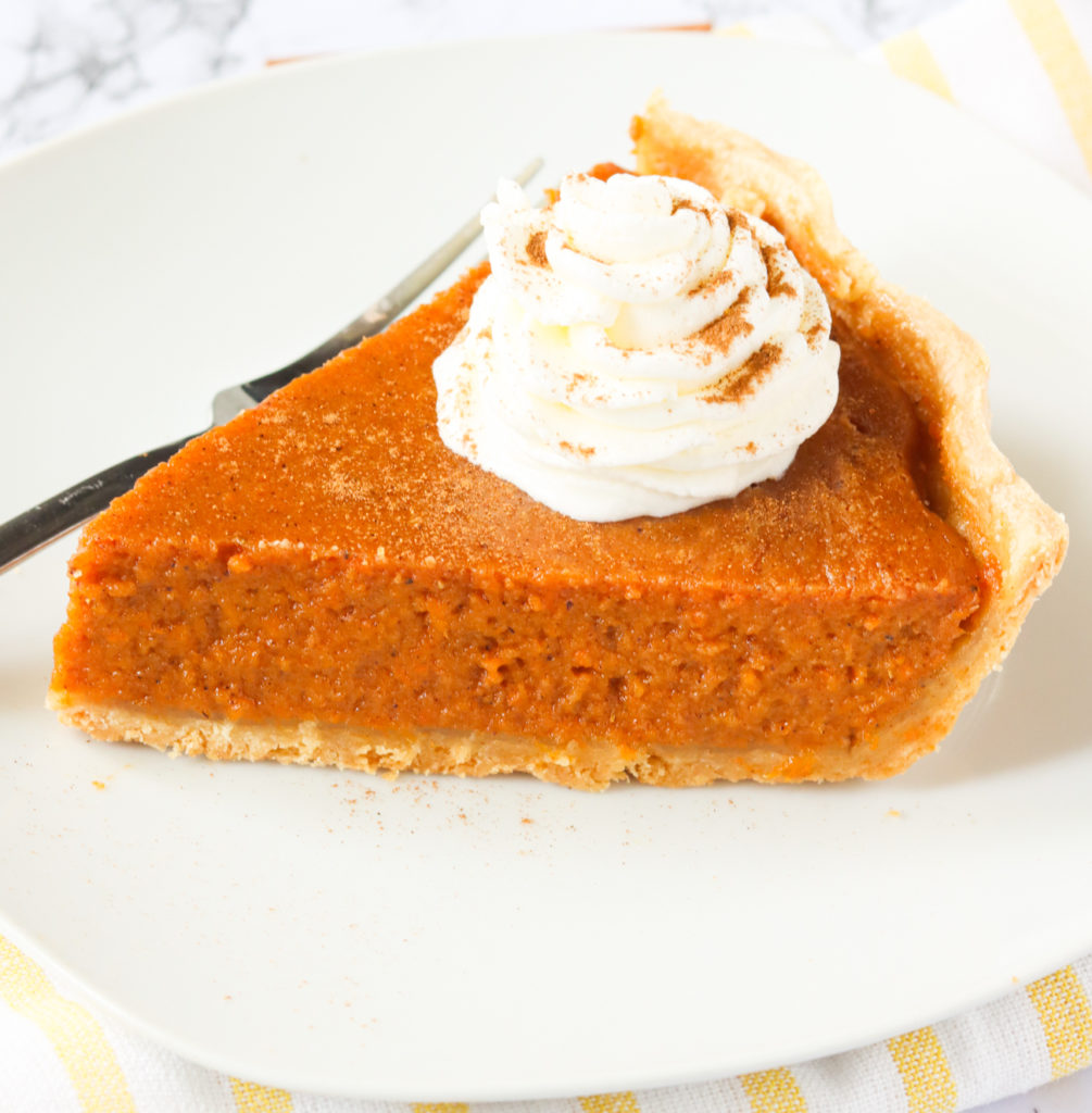 A slice of sweet potato pie with whipped cream on top