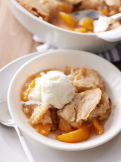 peach cobbler on white place with ice ceam on top