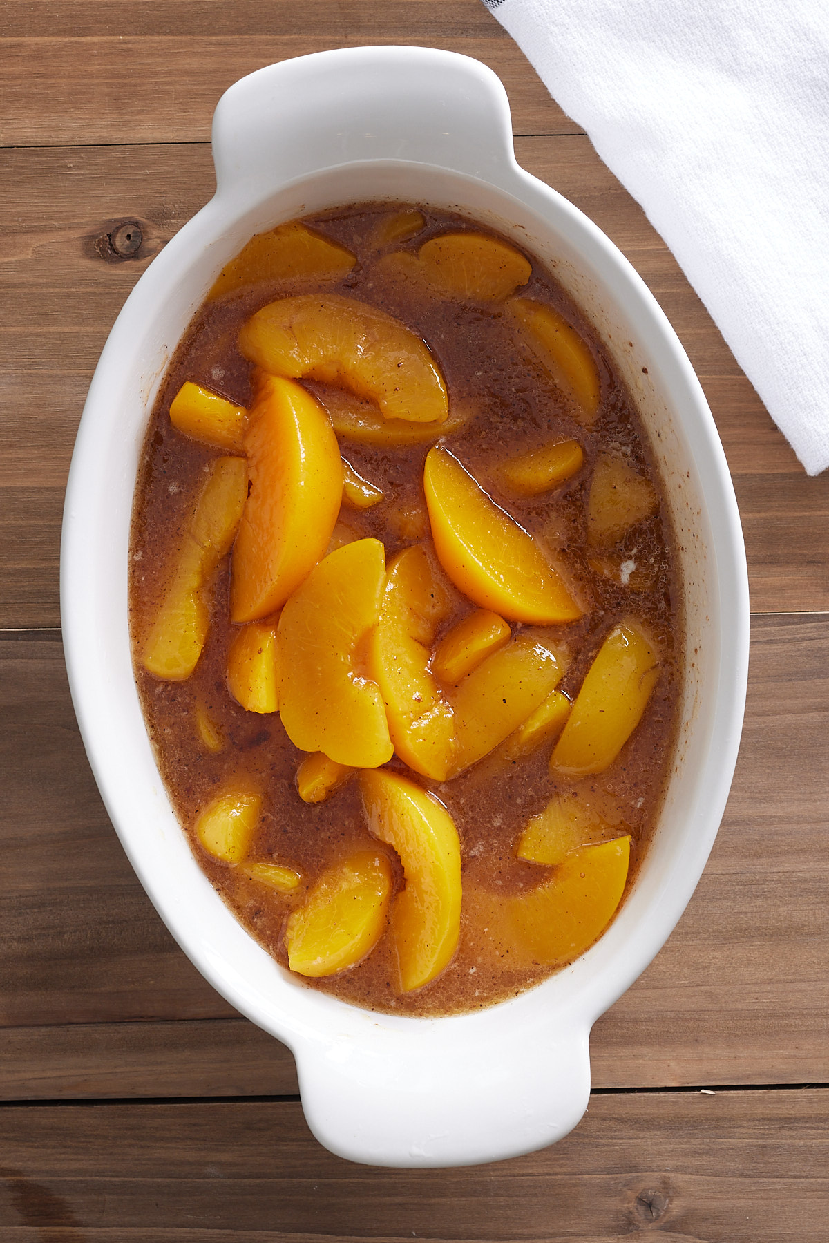 canned peaches and spices in white baking dish