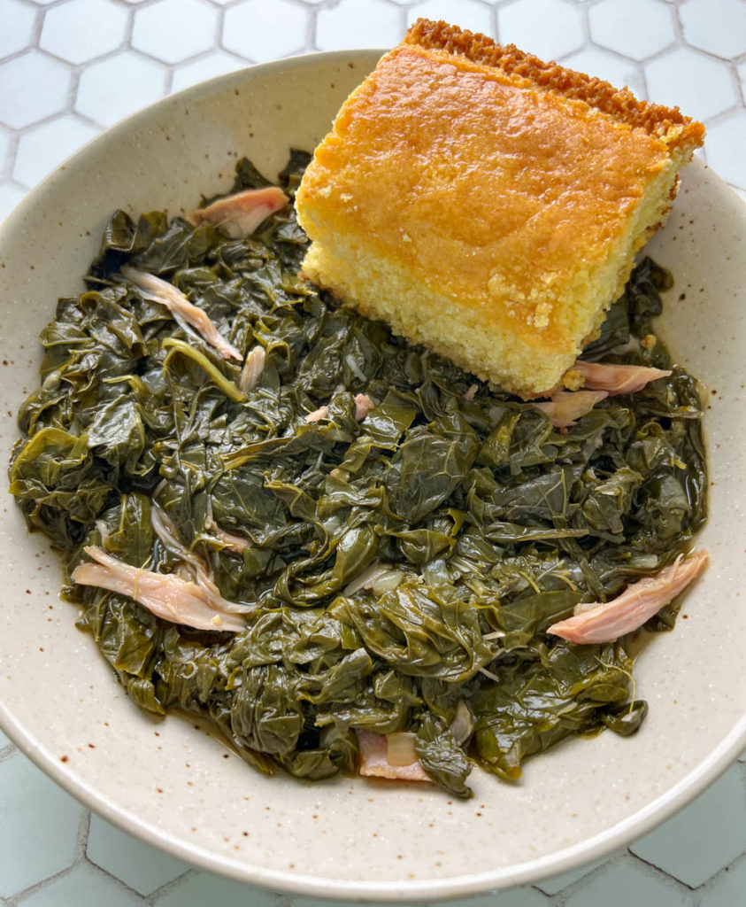 cooked turnip greens in a bowl with a slice of cornbread