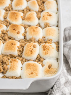 A close up of sweet potato casserole with toasted marshmallows in a white casserole dish