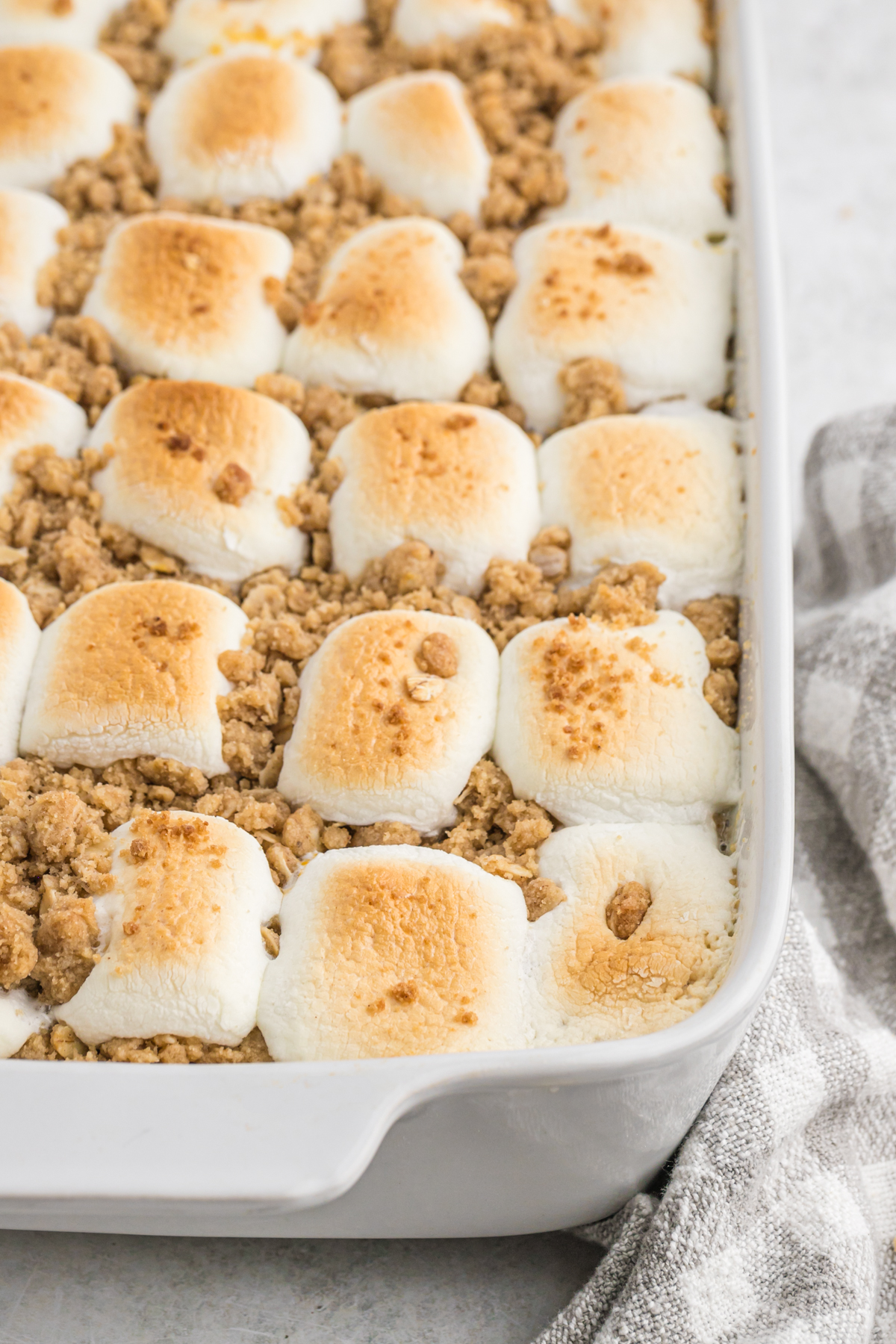 A close up of sweet potato casserole with toasted marshmallows in a white casserole dish
