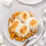 A sweet potato casserole on two white dishes with silver forks ready to serve