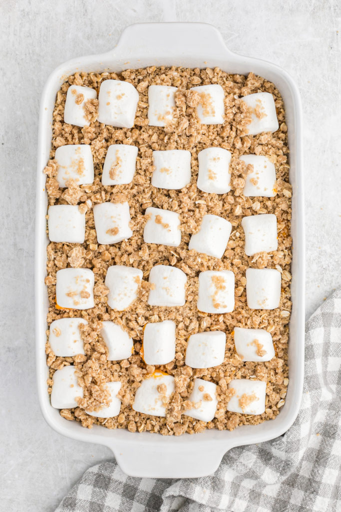 Marshmallows placed on top of a streusel topped sweet potato dish