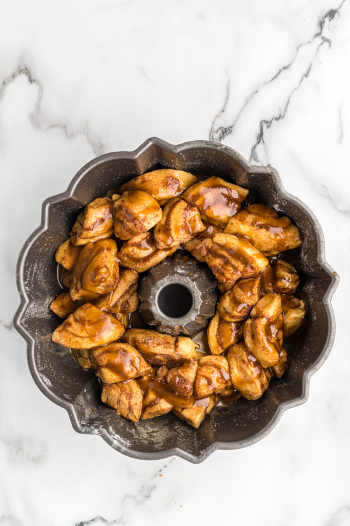 Cinnamon roll dough pressed into a bundt pan with butter on top