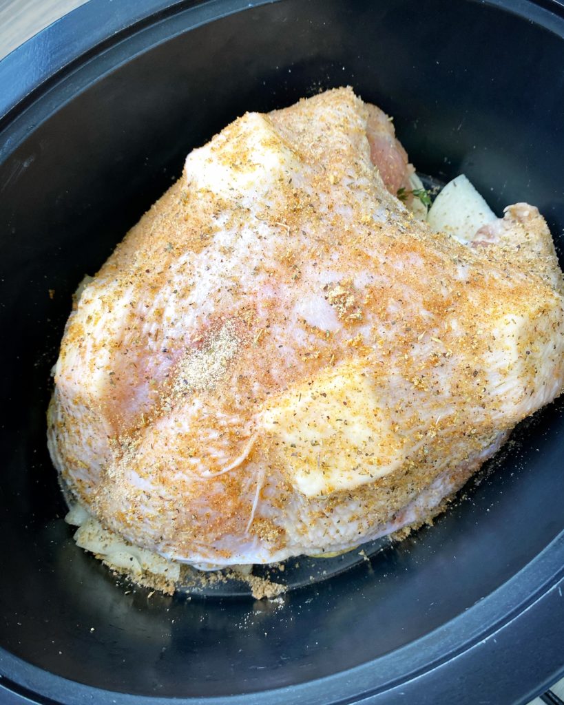 raw, uncooked turkey breast seasoned & stuffed with butter un the skin in the crockpot