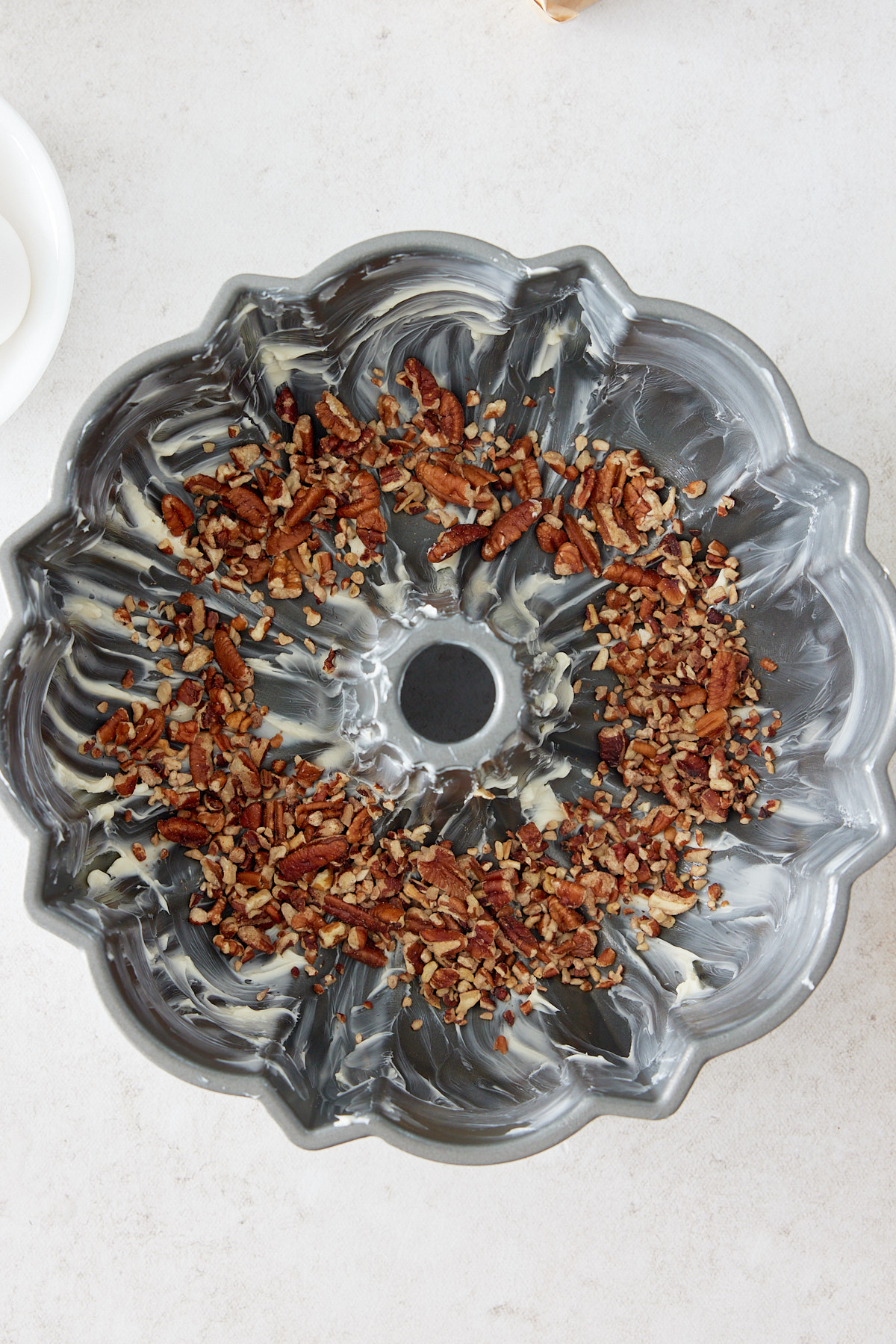 greased bundt pan with chopped nut on inside