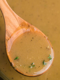 A wooden spoon lifting gravy