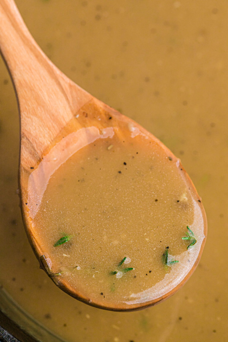 A wooden spoon lifting gravy