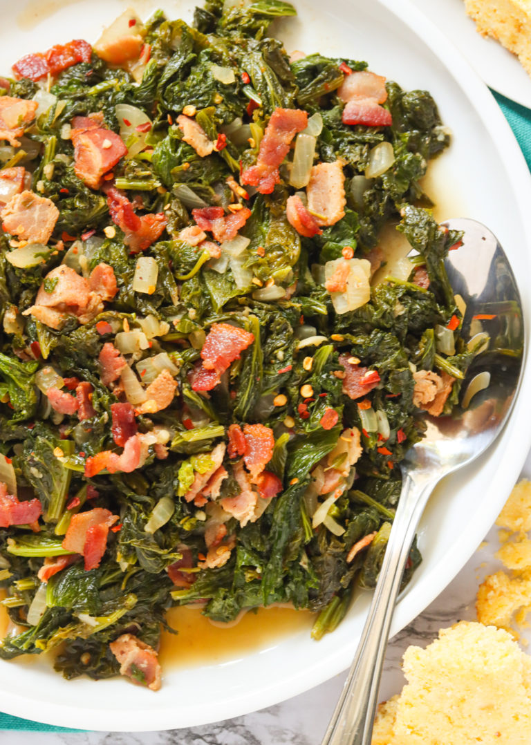 A plateful of mustard greens and bacon with a spoon