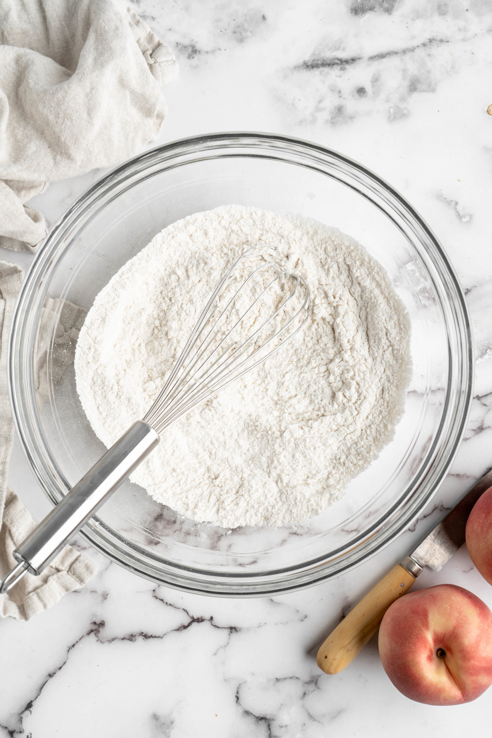 Overhead view of flour in mixing bowl with whisk
