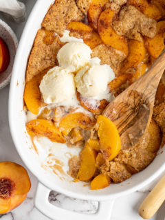 Overhead view of peach cobbler in dish with scoops of ice cream