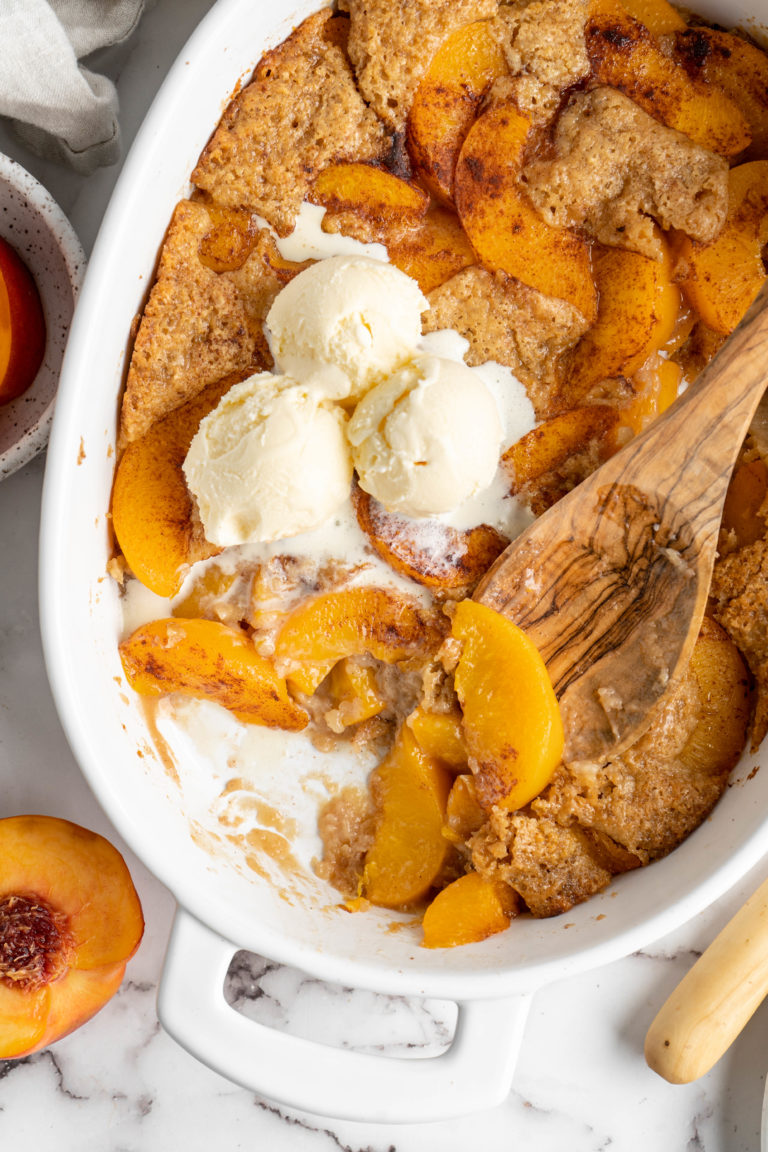 Overhead view of peach cobbler in dish with scoops of ice cream