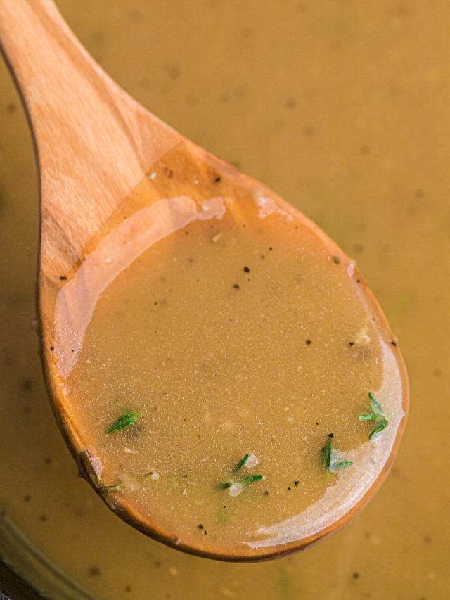 A wooden spoon lifting gravy